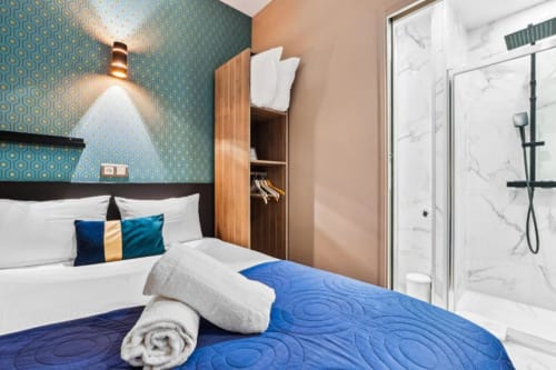 Chambre studio double moderne à la Résidence Aurmat Paris avec accents bleus, penderie en bois et salle de bain en marbre