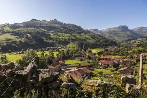 Paisaje del valle de Liérganes con el hotel La Calleja Real rodeado de edificios tradicionales de tejados rojos entre vegetación exuberante