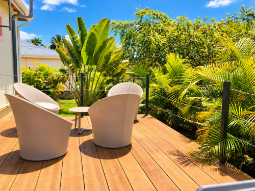 Terrasse de jardin tropical au Quetzal avec transats crème, palmiers et vue sur l'océan à Sainte-Anne, Guadeloupe