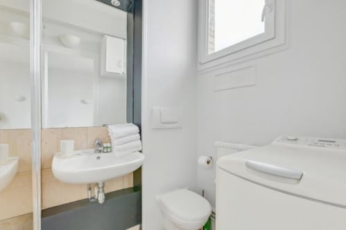Salle de bain moderne du studio cosy à Résidence Aurmat, Paris avec lavabo, toilettes et machine à laver
