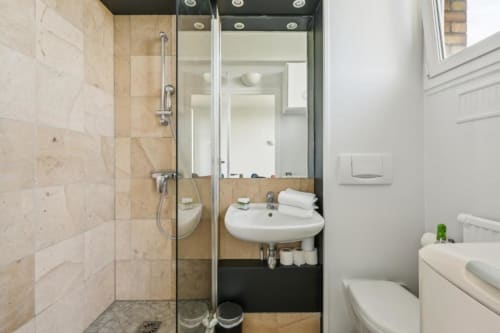 Salle de bain moderne d'un boutique-hôtel parisien avec douche à l'italienne, lavabo courbe et teintes neutres