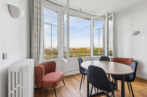 Salle à manger lumineuse avec table ronde, chaises colorées, vue sur Paris, Résidence Aurmat Boulogne