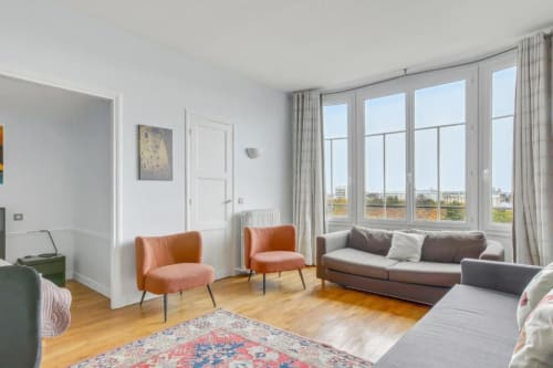 Appartement cosy à Paris à la Résidence Aurmat avec chaises oranges, canapé gris, parquets et vue sur la ville