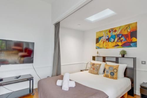 Studio cosy à la Résidence Aurmat Paris avec lit, TV, œuvres d'art colorées et équipements modernes