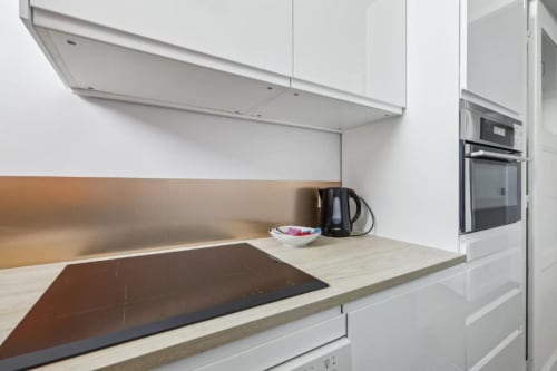 Kitchenette moderne à la Résidence Aurmat Paris avec meubles blancs, plaque induction et électroménagers inox