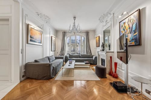 Elegant Parisian apartment living room with herringbone flooring, gray sofa, chandelier, and city views at Résidence Aurmat