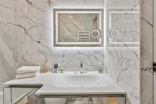 Modern marble bathroom in Trocadéro Apartment at Résidence Aurmat Paris, featuring lit mirrors and white sink