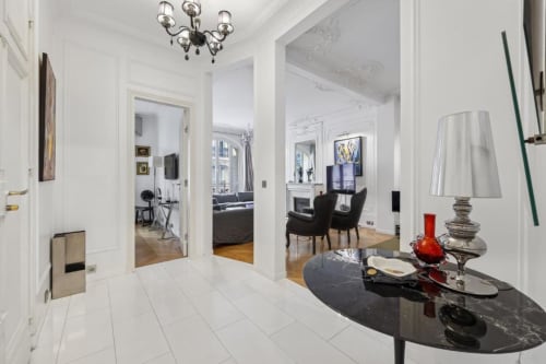 Modern hallway in Trocadéro Apartment at Résidence Aurmat Paris, with white walls, black marble console table, and views into
