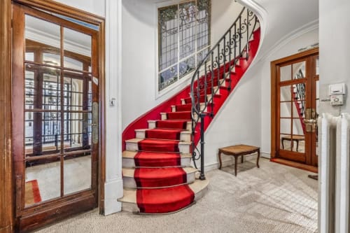 Elegant spiral staircase with red runner carpet and ornate iron railings in Paris boutique hotel lobby