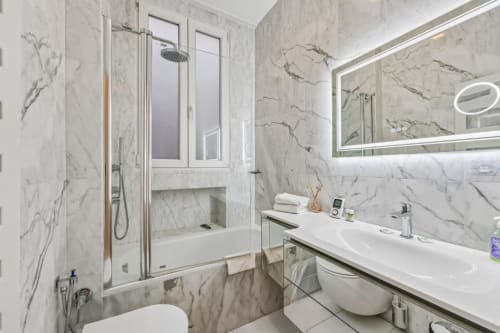 Modern marble bathroom in Trocadéro Apartment at Paris boutique hotel with dual sink vanity, shower and illuminated mirror