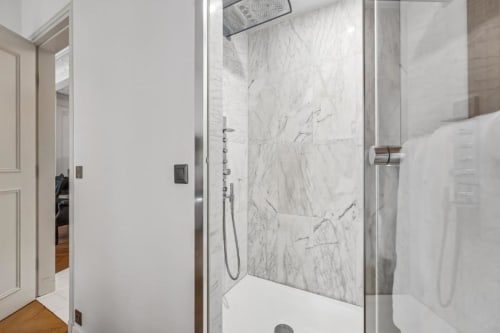 Modern marble walk-in shower with glass enclosure in Trocadéro Apartment at Résidence Aurmat boutique hotel, Paris