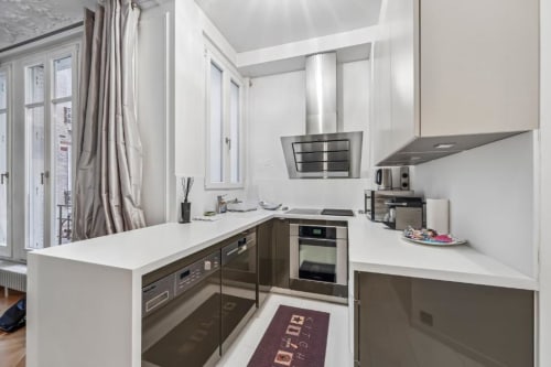 Modern kitchen in Trocadéro Apartment at Résidence Aurmat, Paris with white cabinets, stainless steel appliances, and garden