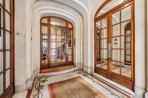 Elegant hallway in Paris boutique hotel with arched ceilings, wooden-framed glass doors, and decorative tiled floor