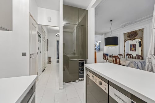 Modern kitchen and living space in Trocadéro Apartment at Résidence Aurmat, Paris, featuring white cabinetry, stainless steel