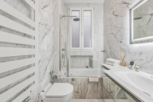 Luxury marble bathroom with shower, toilet, and vanity sink at Résidence Aurmat Trocadéro Apartment in Paris