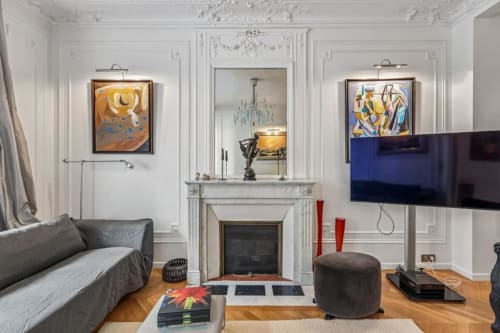 Modern Parisian apartment with fireplace, sofa, artwork, and flat-screen TV in living room
