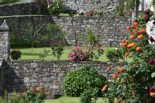 Incantevole giardino di Roseto del Drago con fiori colorati, muri in pietra e prato curato a Ponte In Valtellina