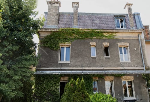La Poterne, guesthouse à Épernay : manoir français couvert de lierre avec cheminées en pierre et toit mansardé