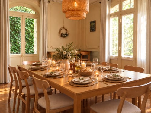 Élégante salle à manger de la Maison d'Hôtes La Poterne à Épernay avec table en bois, couverts dressés et fenêtres recouvertes de lierre