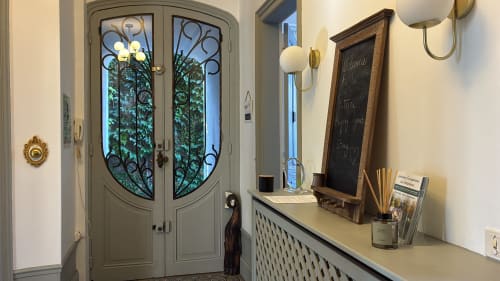 Élégante entrée de La Poterne Épernay avec portes cintrées, panneau de bienvenue et vue sur le jardin à travers la ferronnerie