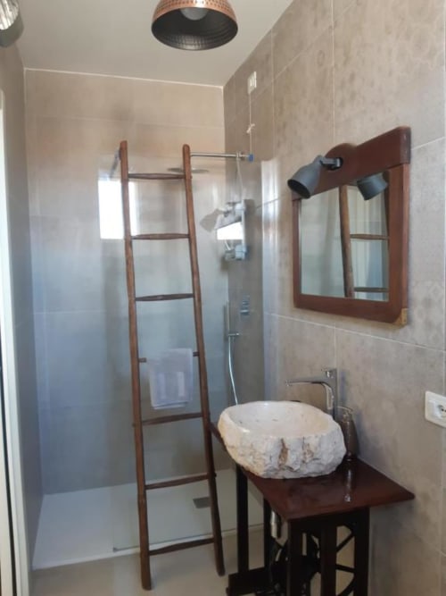 Bagno moderno con lavabo in pietra, scaletta in legno porta-asciugamani e doccia walk-in presso l'Agriturismo il Mandriolo B&B in Italia