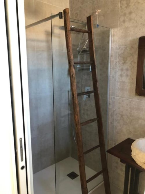 Doccia con box in vetro e scala in legno rustico in camera di agriturismo italiano