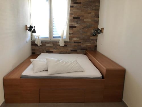 Accogliente camera matrimoniale all'Agriturismo il Mandriolo con letto in legno, biancheria bianca, muro in laterizio e vista sul giardino