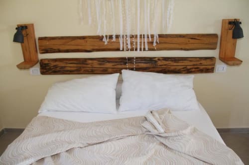 Testata in legno rustico con dettagli in macramé bianco sopra un letto con cuscini bianchi in una camera d'agriturismo italiano