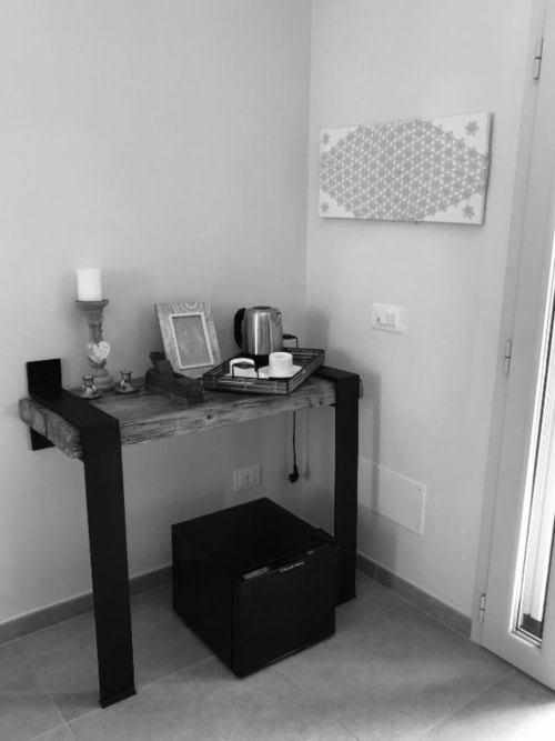 Elegante scrivania nera moderna con bollitore elettrico, cornice fotografica e candela in una luminosa stanza con accesso al patio