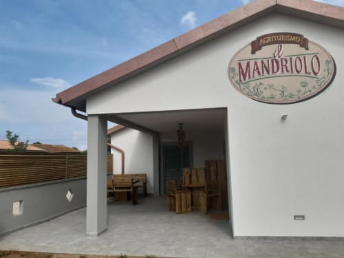 Ingresso dell'Agriturismo il Mandriolo con terrazza, sedie in legno e vista sul giardino