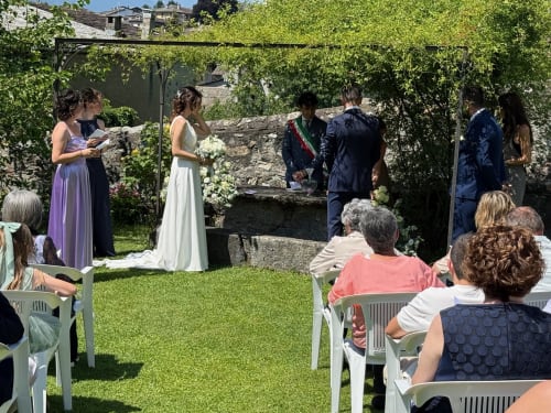 Outdoor wedding ceremony at Roseto del Drago garden in Ponte in Valtellina, guests seated on white chairs