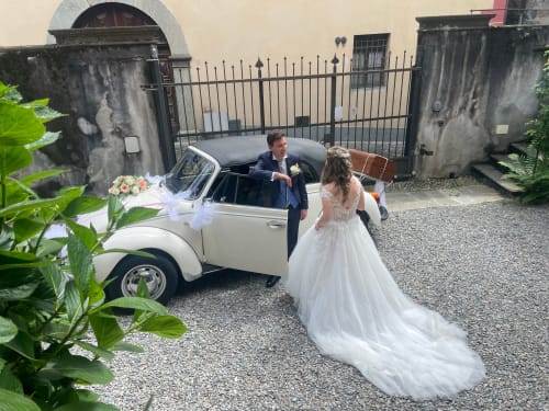 Bride and groom with vintage white Beetle car at Roseto del Drago, Italian countryside wedding venue