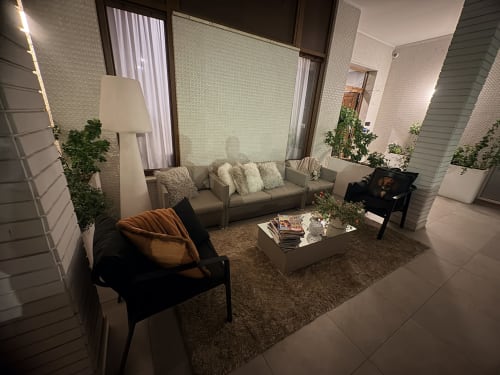 Elegante lounge nel Borea Luxury B&B di Pescara con divano beige, poltrona nera, piante in vaso e illuminazione d'atmosfera