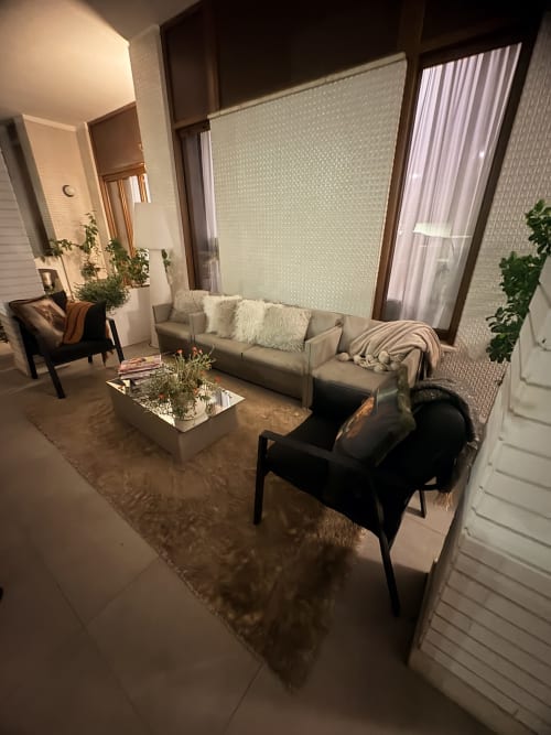 Lussuosa suite al Borea Luxury B&B di Pescara con divano beige, poltrona nera, piante e ampie finestre