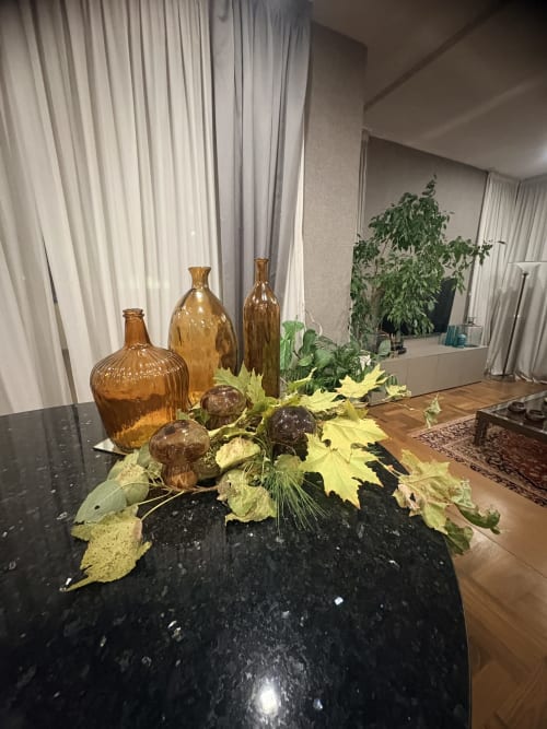 Composizione floreale autunnale con bottiglie ambrate su tavolo nero presso Borea Luxury B&B, Pescara