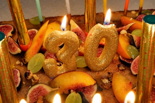 Bougies numéro 50 dorées entourées de figues, d'agrumes et de chandelles effilées colorées à l'Auberge du Parc, Correns
