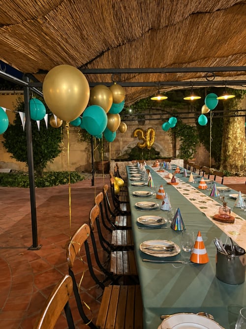 Élégant espace de dîner en plein air à l'Auberge du Parc avec décoration de ballons turquoise et or, table dressée et ambiance rustique