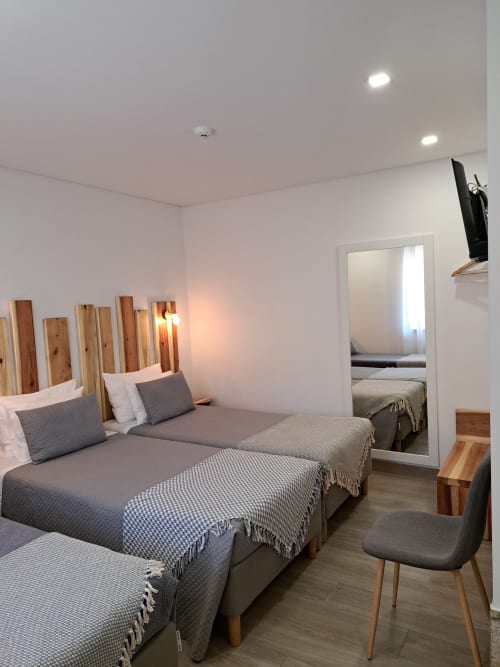 Modern triple bedroom at Agrafonte hotel in Paços de Ferreira with three single beds, wooden headboards, and en-suite