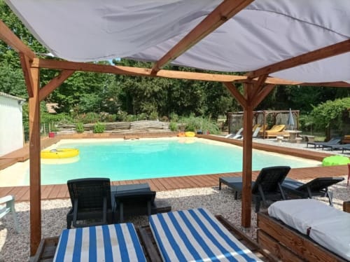 Domaine Le Piboul pool area with wooden pergola, striped loungers, and turquoise water in Fontcouverte