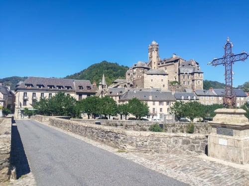 Château médiéval et pont enjambant la rivière Lot au village d'Estaing, France avec architecture en pierre historique et ciel bleu dégagé