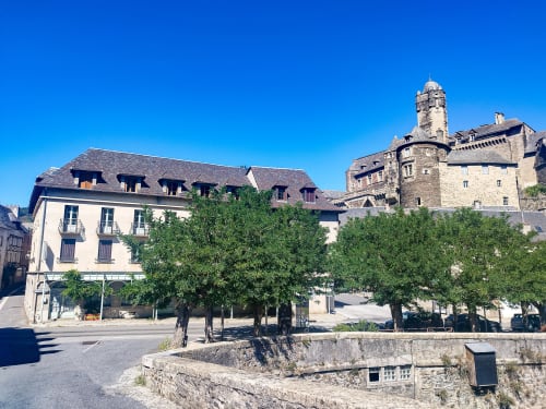 Façade de l'Hôtel du Pont d'Estaing avec tour en pierre, cour arborée et architecture historique française