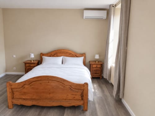 Chambre spacieuse à l'Hôtel du Pont d'Estaing avec lit en bois, draps blancs, deux tables de nuit, climatisation et vue sur la rivière