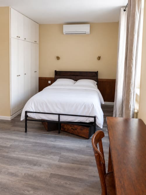 Chambre moderne à l'Hôtel du pont d'Estaing avec lit queen-size, draps blancs, mobilier en bois, climatisation et armoire intégrée.