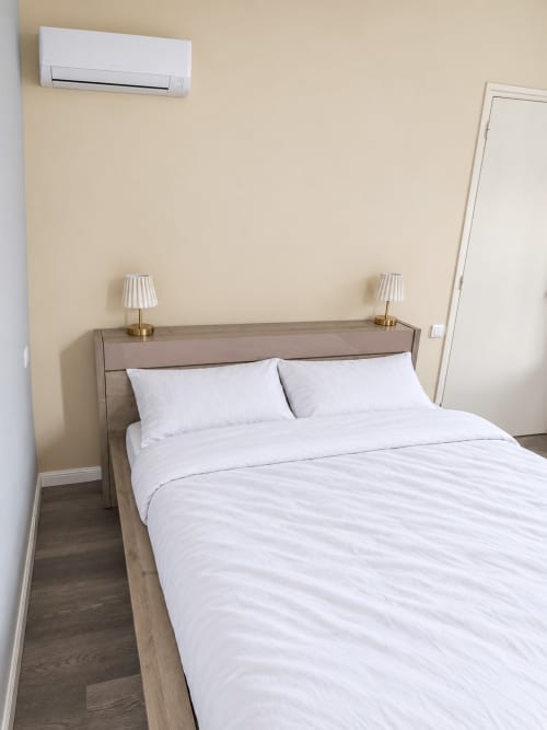 Chambre moderne à l'Hôtel du pont d'Estaing avec literie blanche, tête de lit en bois, lampes en laiton et climatisation murale