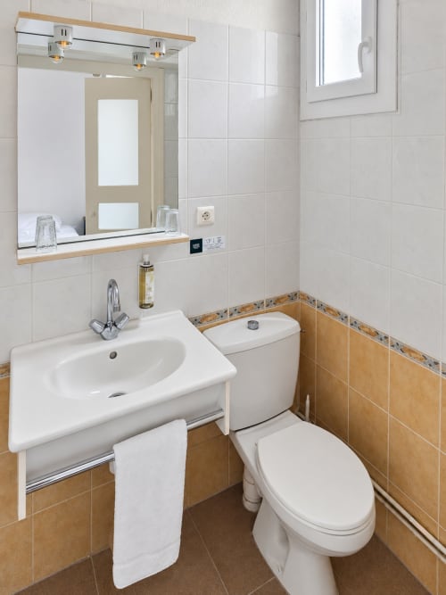 Salle de bains moderne à l'Hôtel du pont d'Estaing avec lavabo blanc, toilettes et carrelage beige