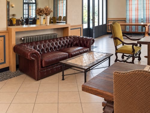 Hall élégant de l'Hôtel du pont d'Estaing avec canapé Chesterfield en cuir bordeaux, réception en bois et mobilier d'époque