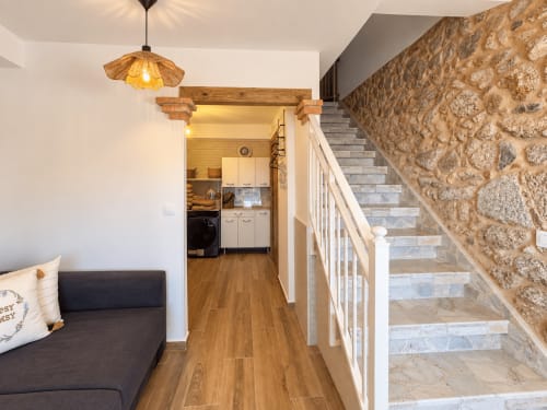 Interior de cabaña moderna en As Mariñas con salón diáfano, escalera de piedra, suelos de madera y cocina equipada