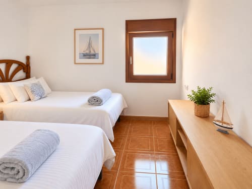 Dormitorio luminoso en As Mariñas con dos camas, muebles de madera, decoración náutica y vistas al mar