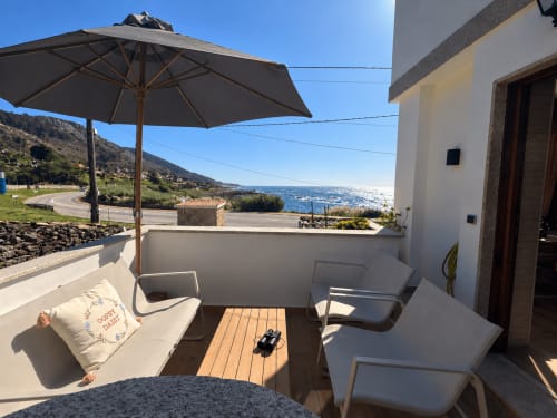Terraza de la casita Holibai en As Mariñas con vistas al mar, sombrilla, tumbonas y paisaje costero