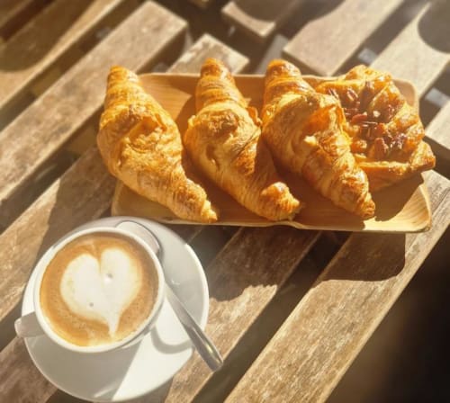 Cornetti dorati e latte con latte art su tavolo di legno alla colazione di Amor Rome Apartment